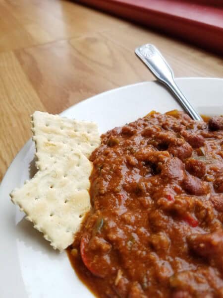 A bowl of chili with crackers.